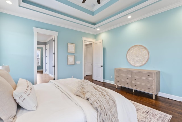 bedroom featuring crown molding, a raised ceiling, baseboards, and wood finished floors