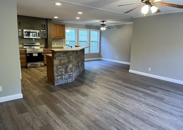 kitchen featuring dark wood finished floors, crown molding, baseboards, and stainless steel appliances