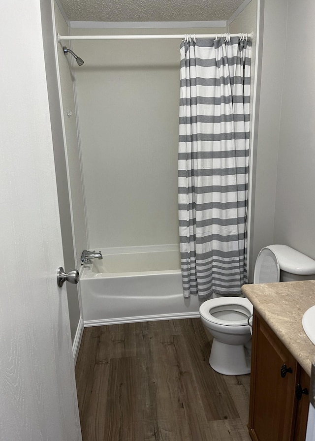 bathroom featuring vanity, wood finished floors, shower / bath combo with shower curtain, a textured ceiling, and toilet