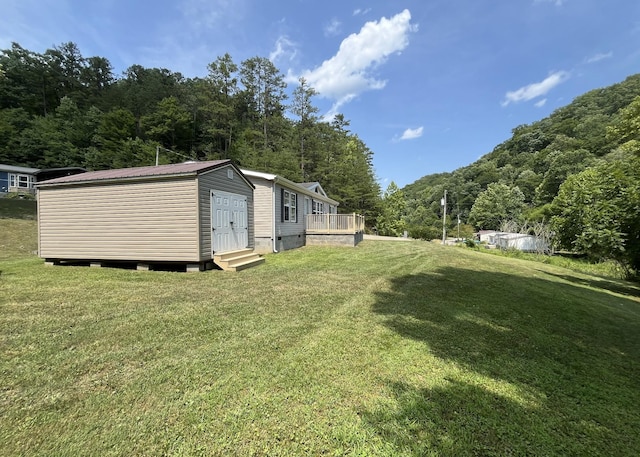 view of yard featuring a wooded view and entry steps