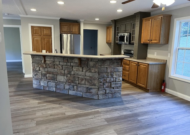 kitchen featuring crown molding, a center island, wood finished floors, and stainless steel appliances