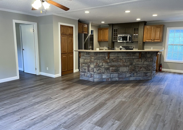 kitchen featuring stainless steel appliances, crown molding, light countertops, glass insert cabinets, and dark wood-style flooring