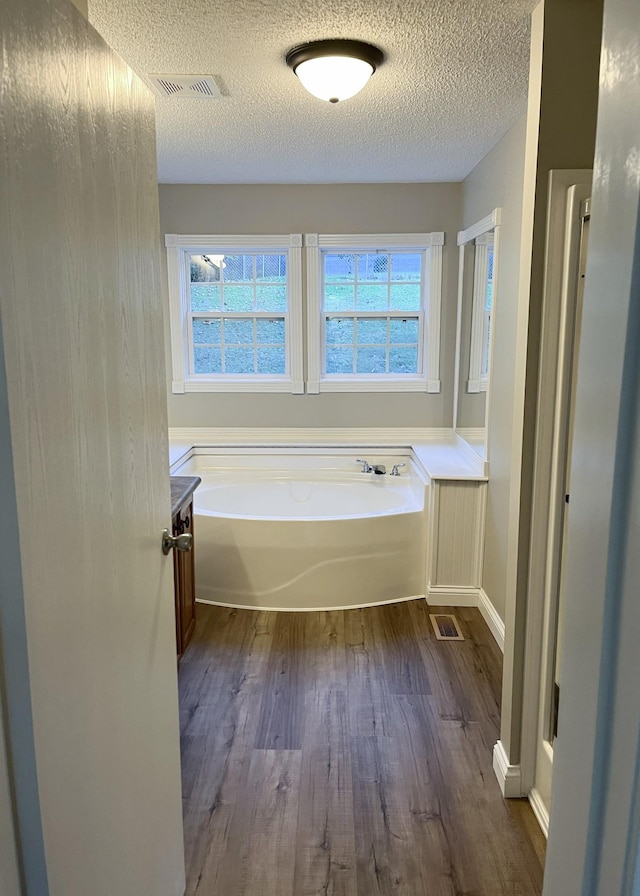 full bathroom featuring visible vents, plenty of natural light, and a garden tub