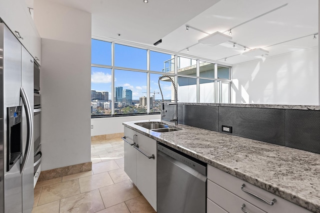 kitchen featuring white cabinetry, light stone countertops, stainless steel appliances, and sink