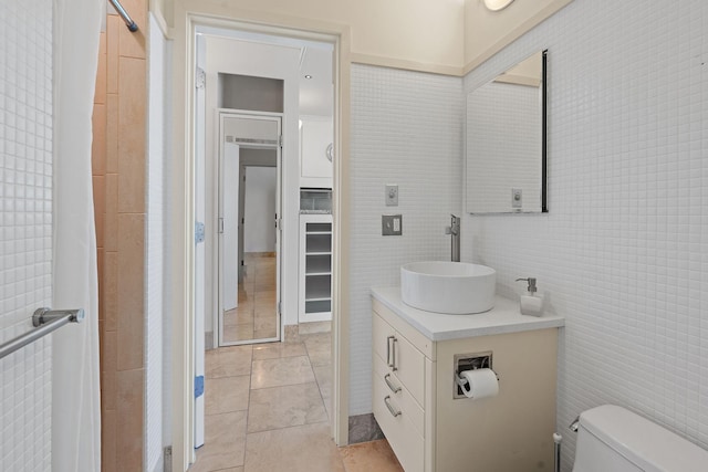 bathroom with vanity, tile patterned flooring, tile walls, and toilet