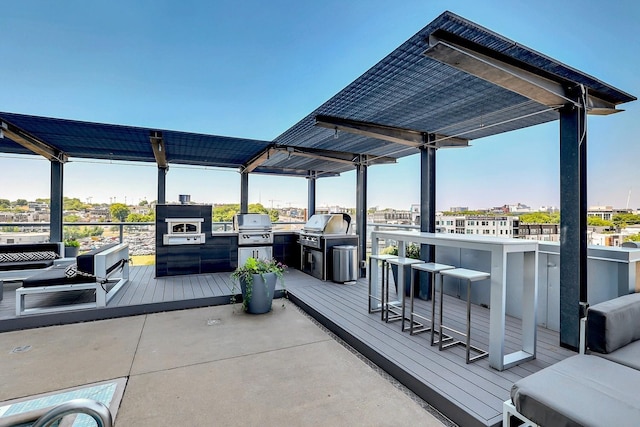 view of patio with an outdoor kitchen, a grill, exterior bar, and a pergola