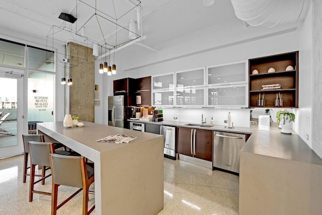 kitchen with appliances with stainless steel finishes, a kitchen bar, decorative light fixtures, and sink