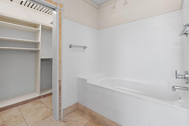 bathroom with a relaxing tiled tub and tile patterned floors