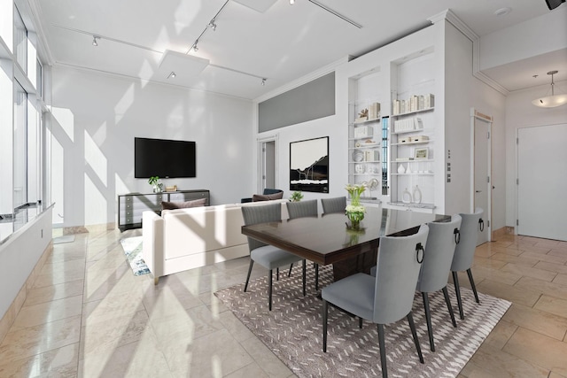 dining area with crown molding and track lighting