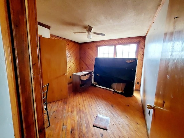 interior space with hardwood / wood-style floors, wooden walls, and ceiling fan