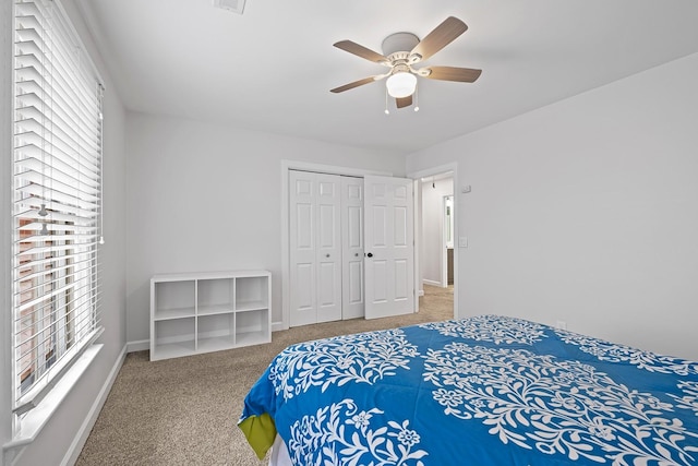 carpeted bedroom featuring ceiling fan, a closet, and multiple windows