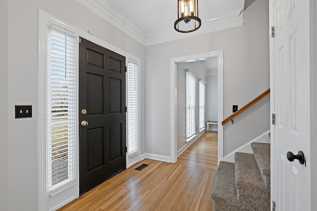 entrance foyer with ornamental molding, light hardwood / wood-style flooring, and a wealth of natural light