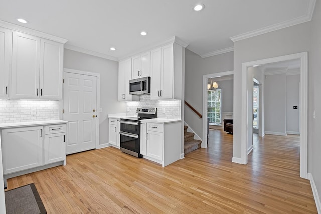 kitchen with appliances with stainless steel finishes, white cabinetry, ornamental molding, light hardwood / wood-style floors, and decorative backsplash