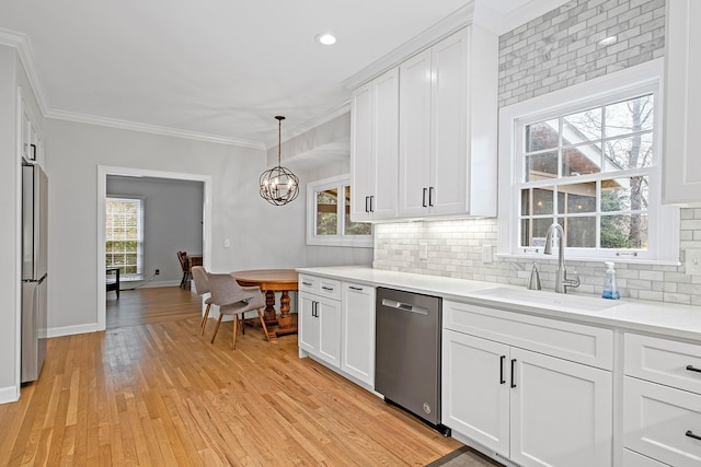 kitchen featuring sink, appliances with stainless steel finishes, hanging light fixtures, white cabinets, and light wood-type flooring