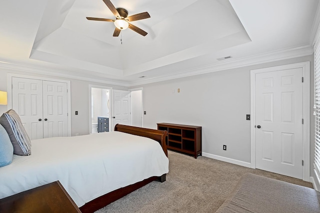 carpeted bedroom featuring ceiling fan, ensuite bath, ornamental molding, and a tray ceiling