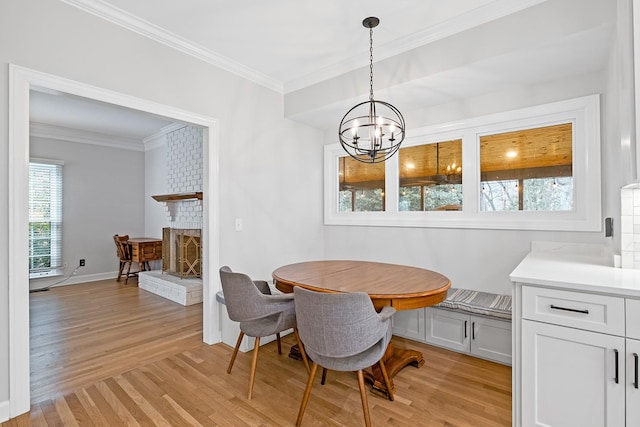 dining space with an inviting chandelier, a brick fireplace, light hardwood / wood-style flooring, ornamental molding, and breakfast area