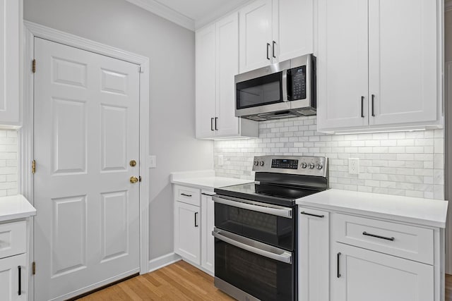 kitchen with light hardwood / wood-style flooring, ornamental molding, stainless steel appliances, decorative backsplash, and white cabinets