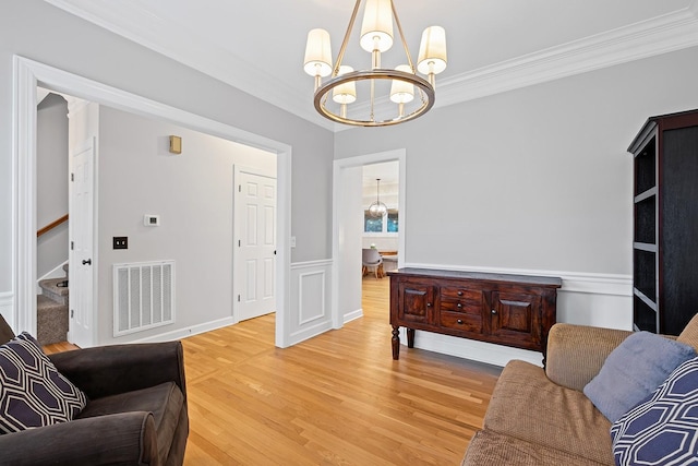 sitting room with ornamental molding, a chandelier, and hardwood / wood-style floors