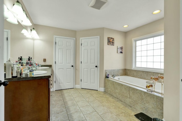 bathroom with tile patterned flooring, vanity, and a relaxing tiled tub