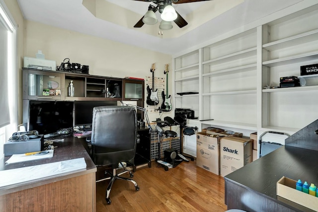 office area with ceiling fan, a raised ceiling, and hardwood / wood-style floors