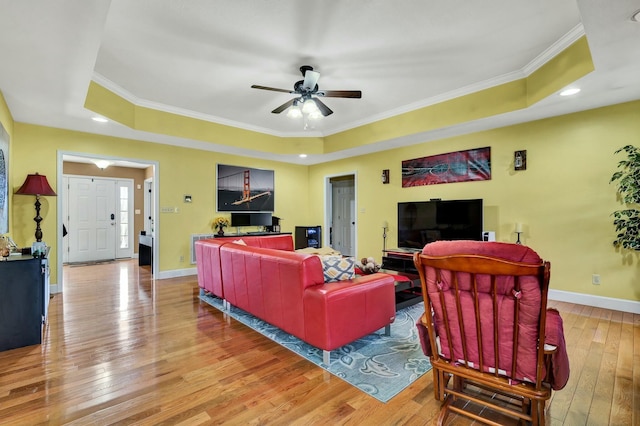 living room with a tray ceiling, light hardwood / wood-style flooring, and ornamental molding