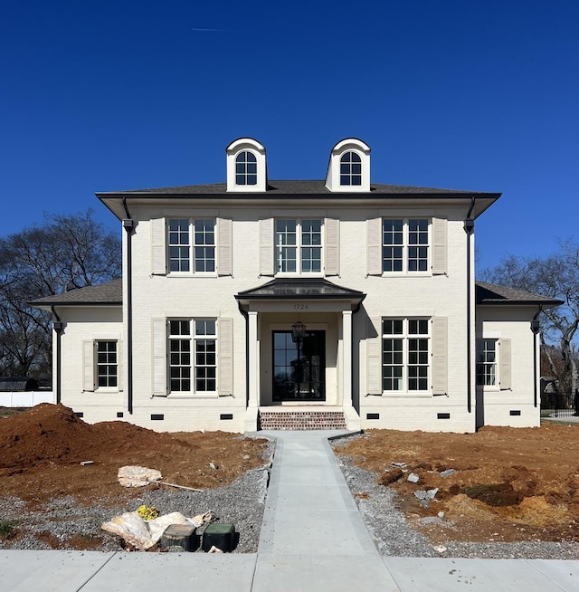 view of front of property with brick siding, crawl space, and a shingled roof