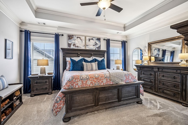 bedroom featuring multiple windows, ornamental molding, light colored carpet, and a tray ceiling