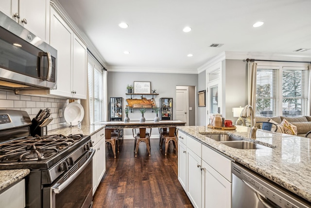 kitchen with sink, white cabinets, ornamental molding, light stone counters, and stainless steel appliances