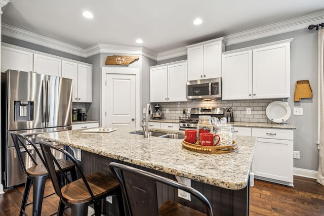 kitchen with an island with sink, appliances with stainless steel finishes, sink, and white cabinets