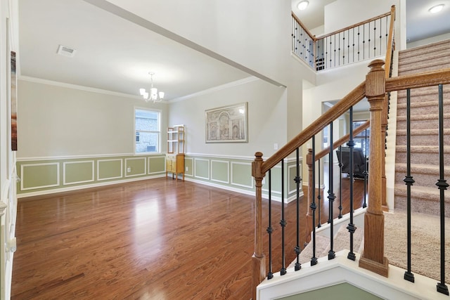 interior space with an inviting chandelier, wood-type flooring, and ornamental molding