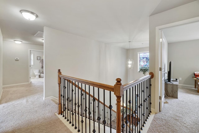 hall with light colored carpet and a chandelier