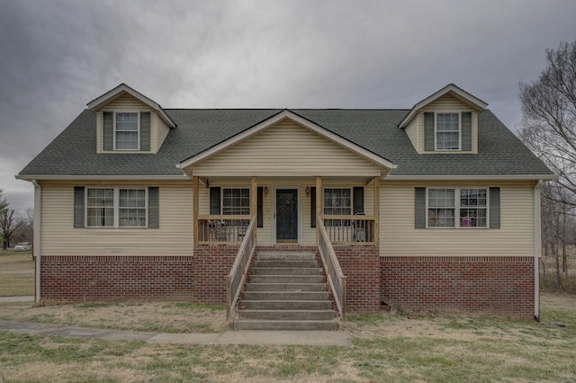 cape cod house featuring a front yard and covered porch