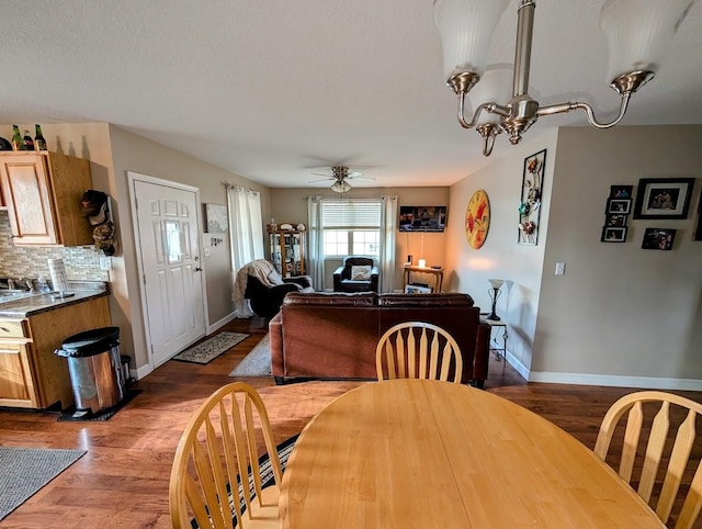 dining area featuring wood-type flooring and ceiling fan with notable chandelier