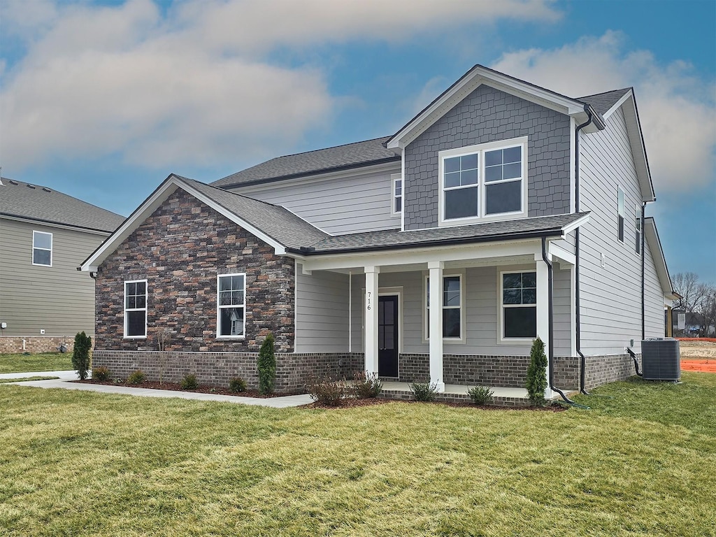 craftsman-style house featuring a porch, a front yard, and central air condition unit