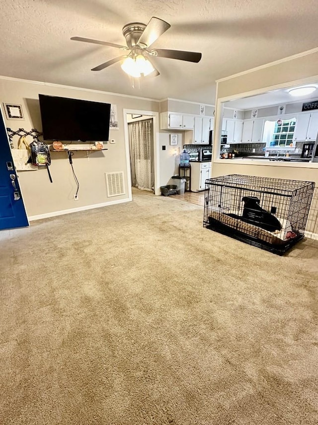 carpeted living room with crown molding, ceiling fan, and a textured ceiling