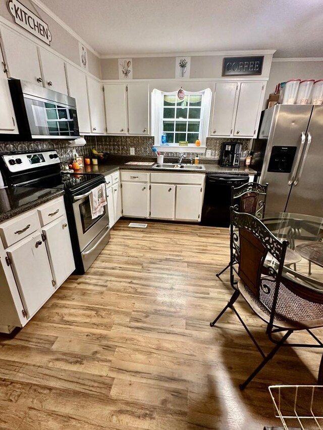 kitchen featuring ornamental molding, appliances with stainless steel finishes, white cabinets, light hardwood / wood-style floors, and backsplash