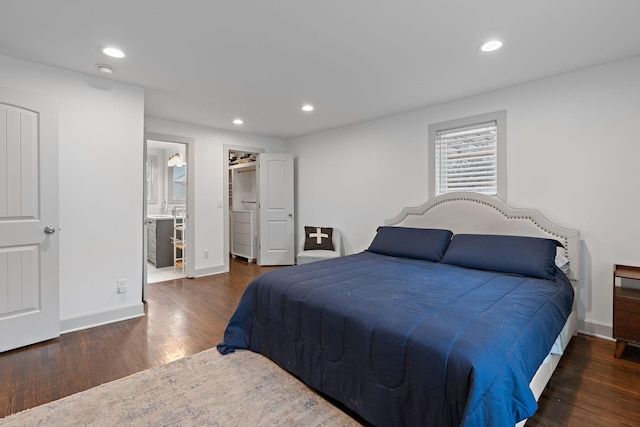 bedroom featuring dark wood-type flooring, a walk in closet, and ensuite bath