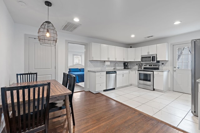 kitchen with white cabinetry, appliances with stainless steel finishes, and hanging light fixtures