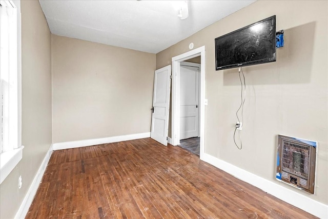 unfurnished bedroom with hardwood / wood-style floors and heating unit