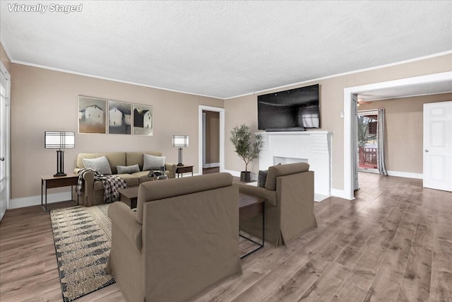 living room with crown molding, a fireplace, hardwood / wood-style floors, and a textured ceiling