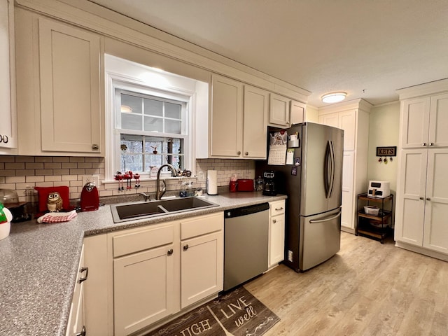 kitchen featuring stainless steel appliances, light hardwood / wood-style floors, sink, and backsplash