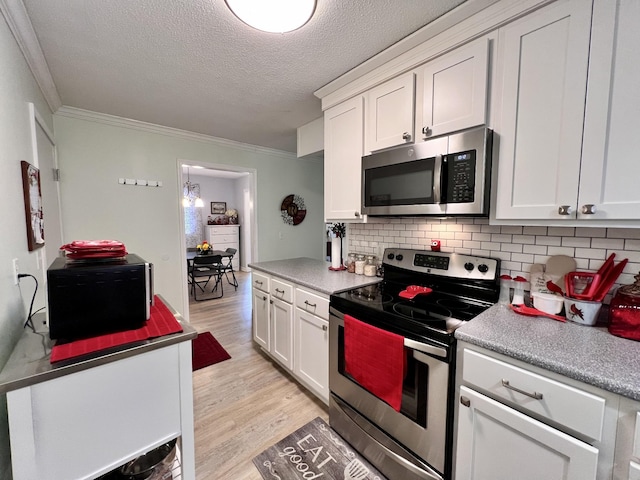 kitchen with stainless steel appliances, crown molding, white cabinets, and light hardwood / wood-style flooring