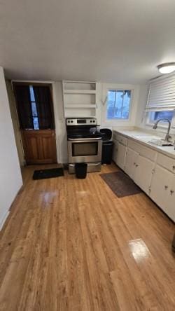 kitchen featuring stainless steel range with electric stovetop, sink, light hardwood / wood-style floors, and white cabinets