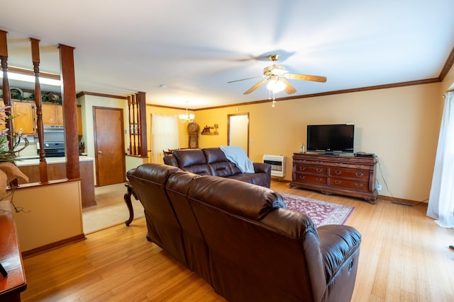 living room featuring crown molding, ceiling fan with notable chandelier, light hardwood / wood-style flooring, and heating unit