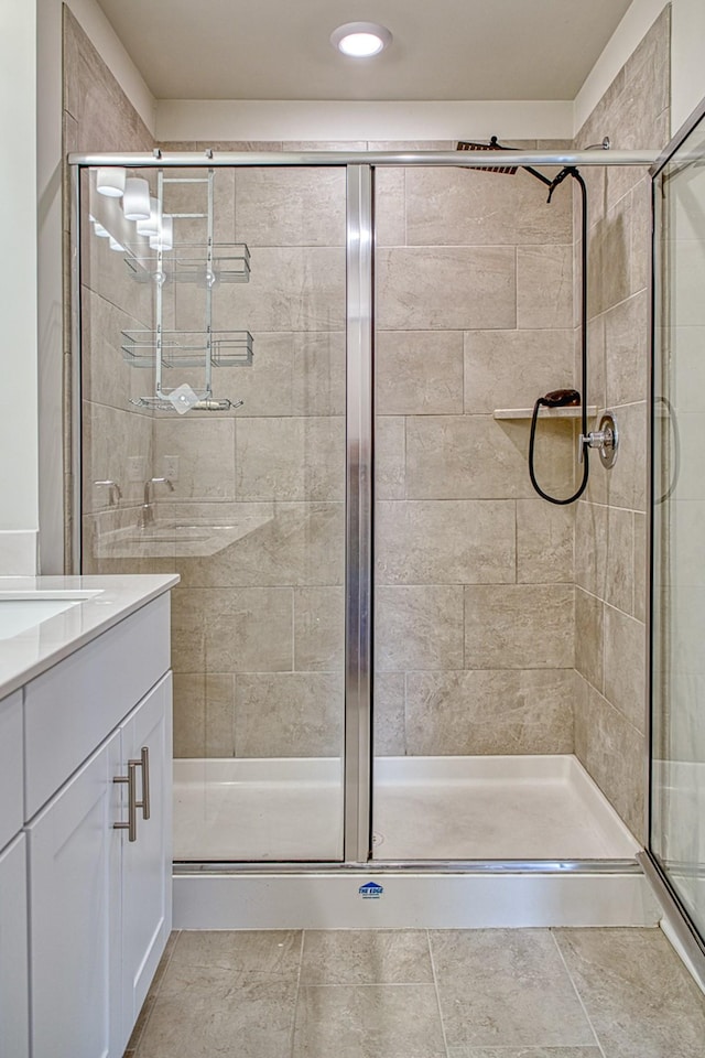 bathroom featuring walk in shower, vanity, and tile patterned flooring