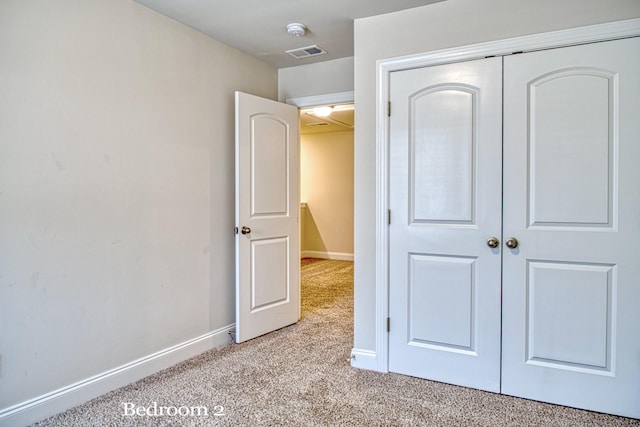 unfurnished bedroom with light carpet and a closet