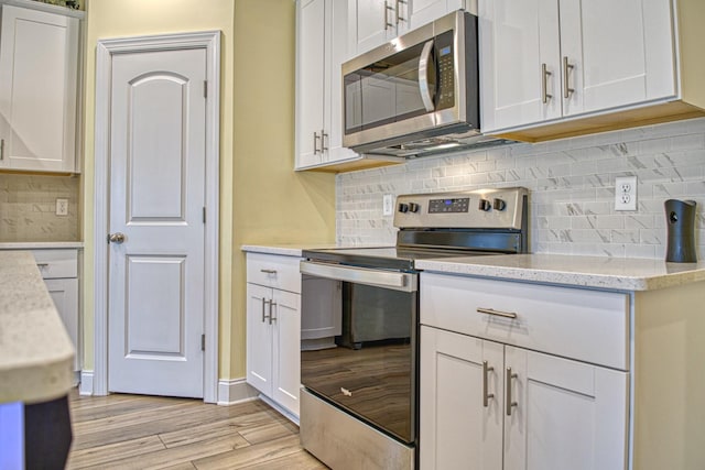 kitchen with light stone counters, stainless steel appliances, light wood-type flooring, and white cabinets