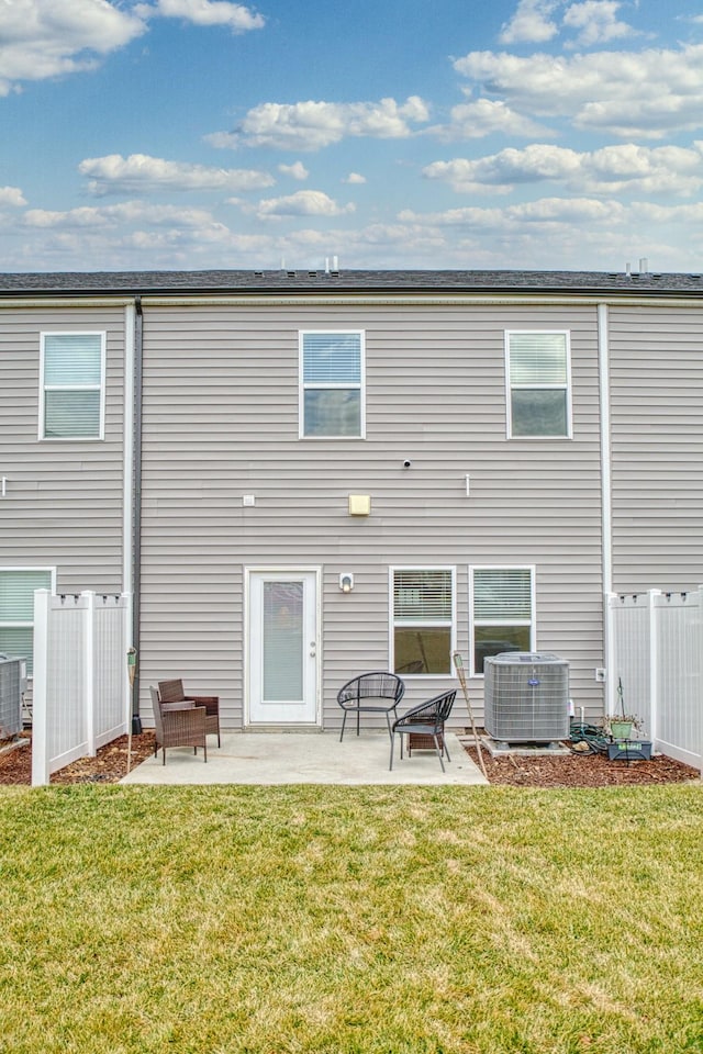 back of house featuring cooling unit, a patio area, and a lawn