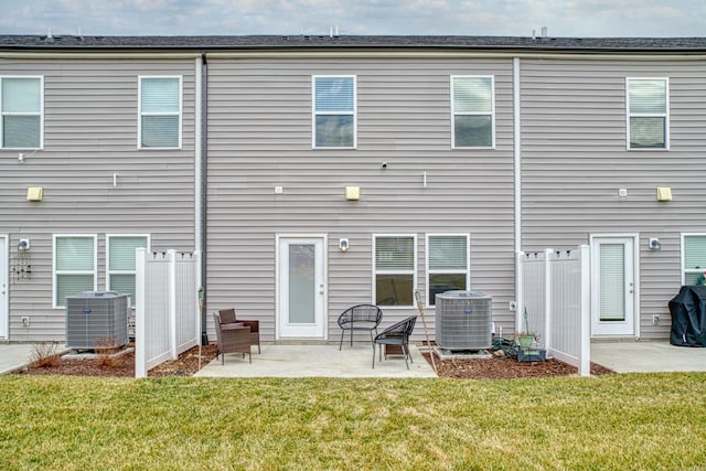 rear view of property with central AC, a patio area, and a lawn