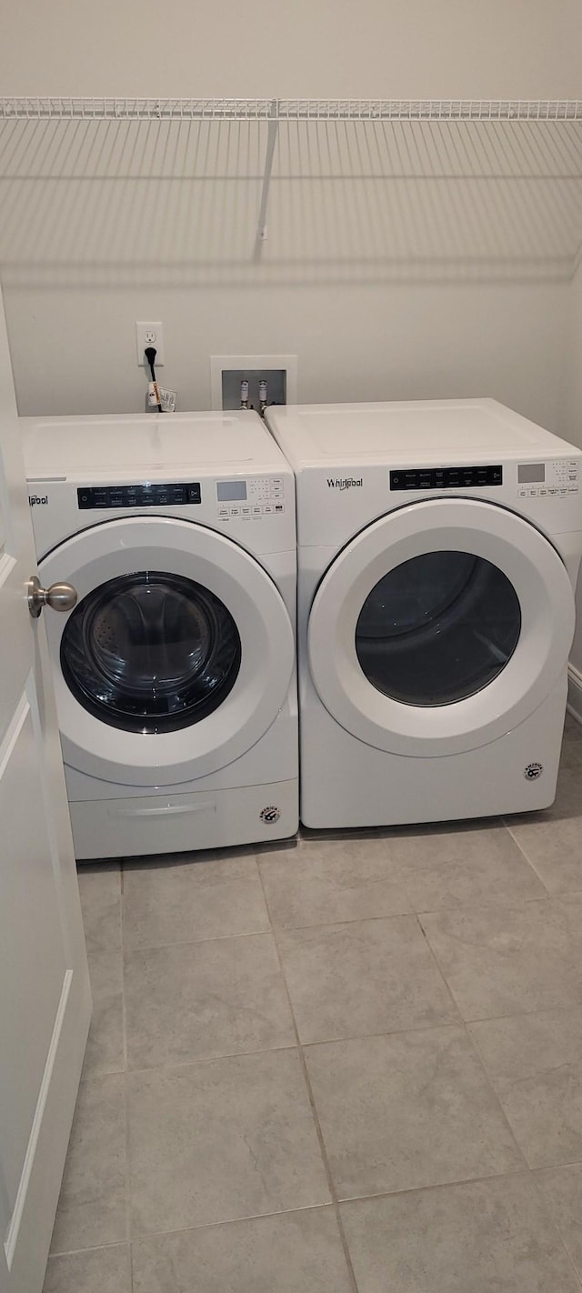 clothes washing area featuring washing machine and dryer and light tile patterned flooring